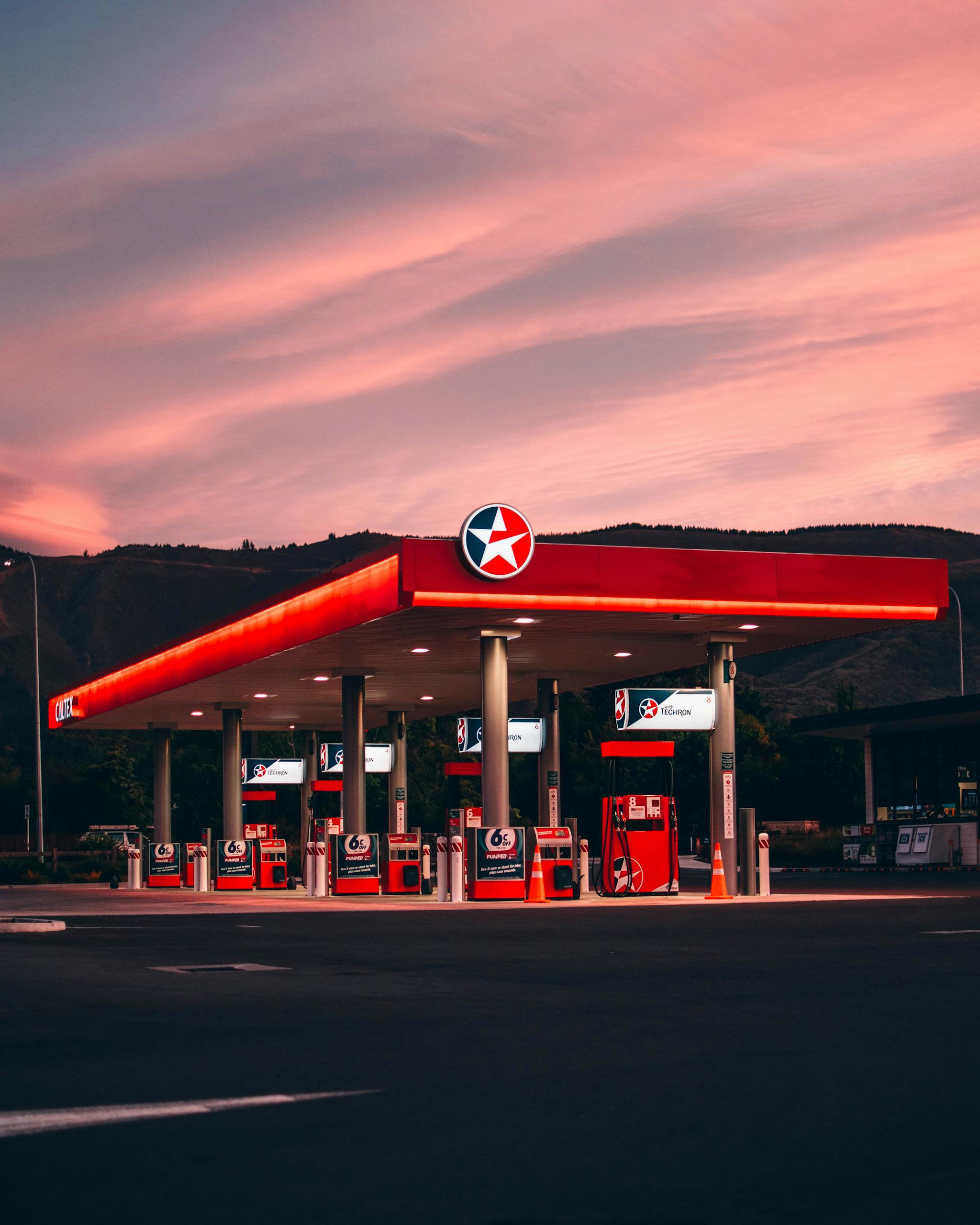 A gas station illuminated under vibrant sunset skies in Nelson, New Zealand.