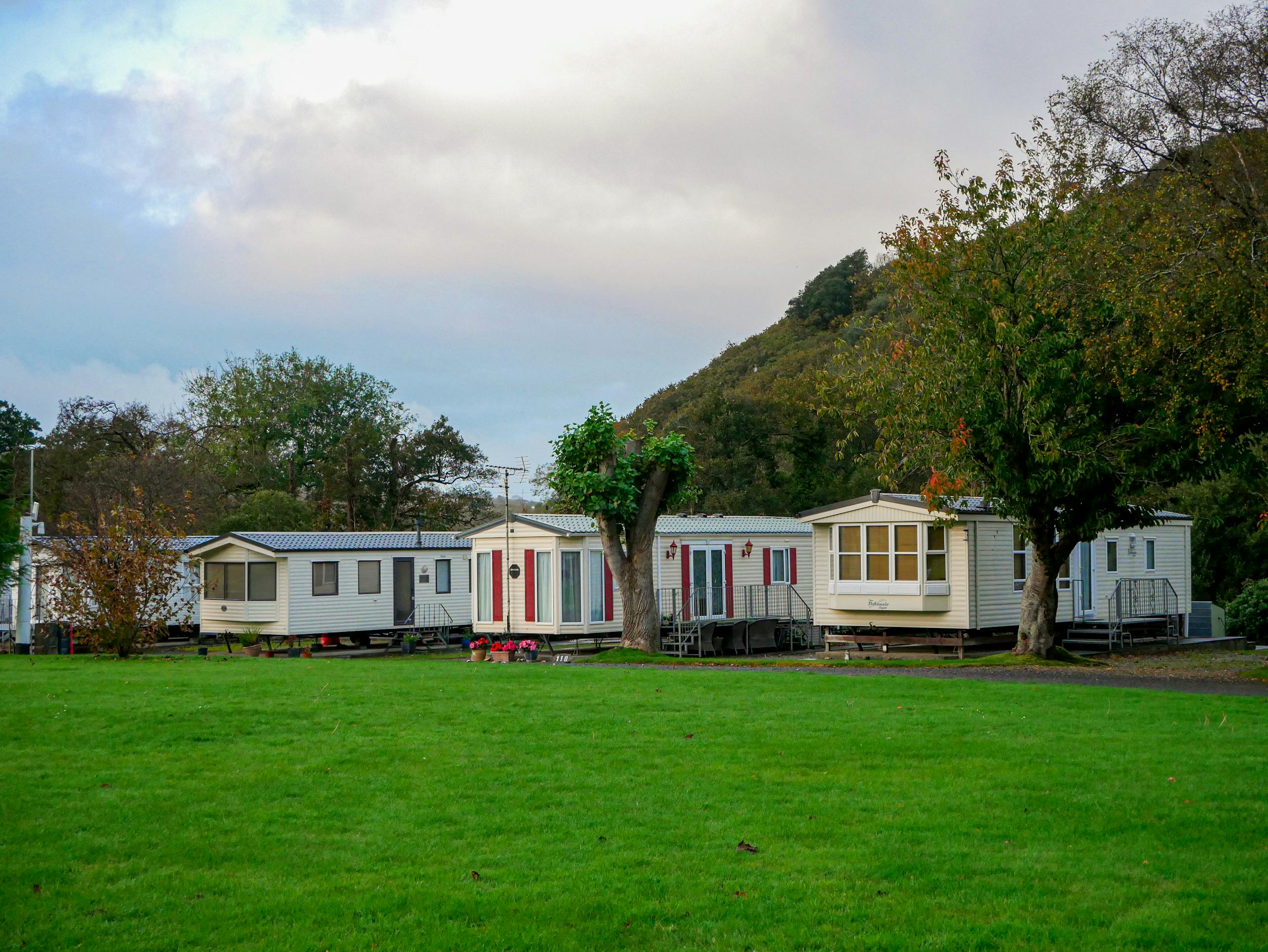 Mobile homes surrounded by lush greenery and hills, depicting a serene countryside getaway.