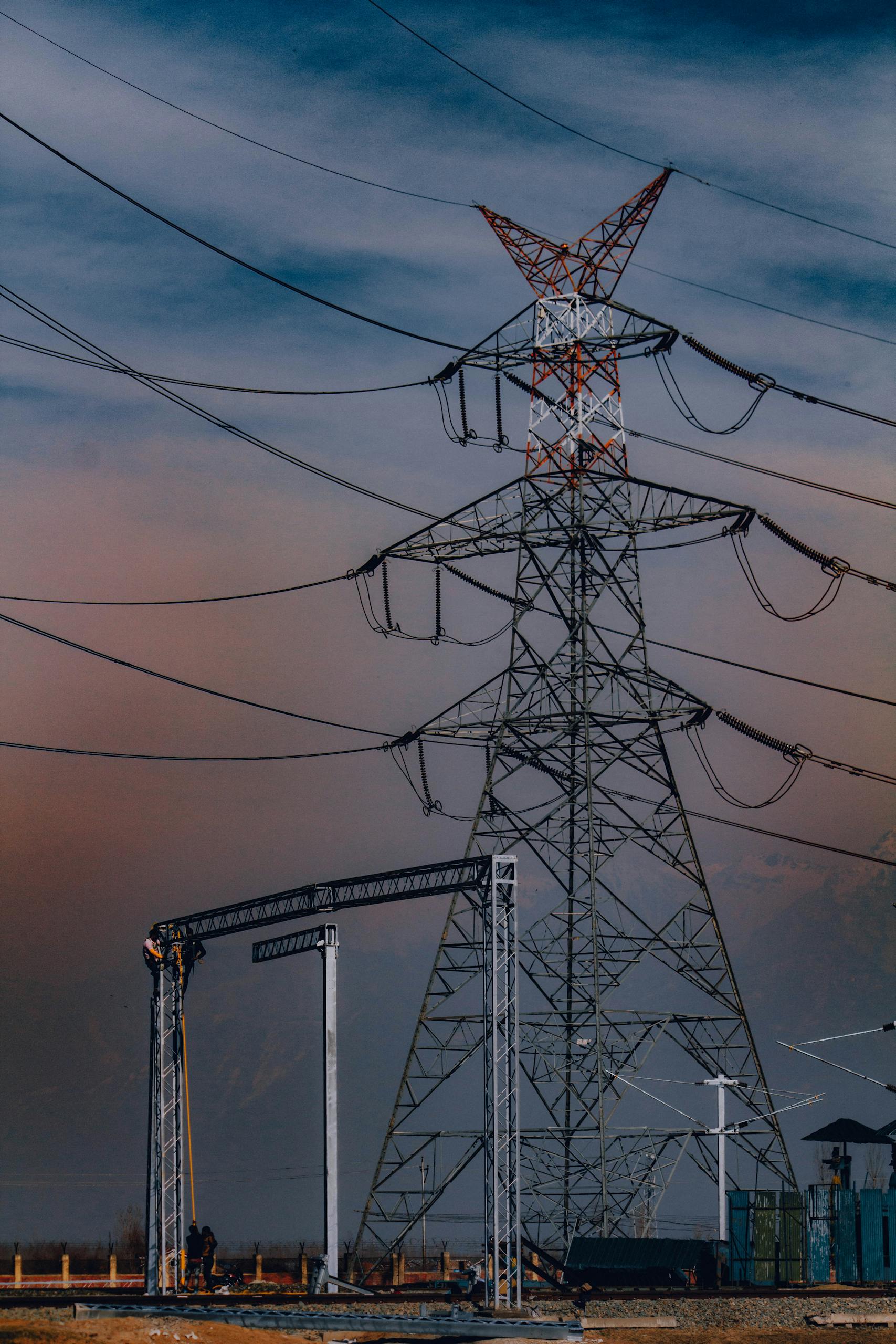 Towering power lines stand against a dramatic sky in Srinagar, showcasing electricity's reach.