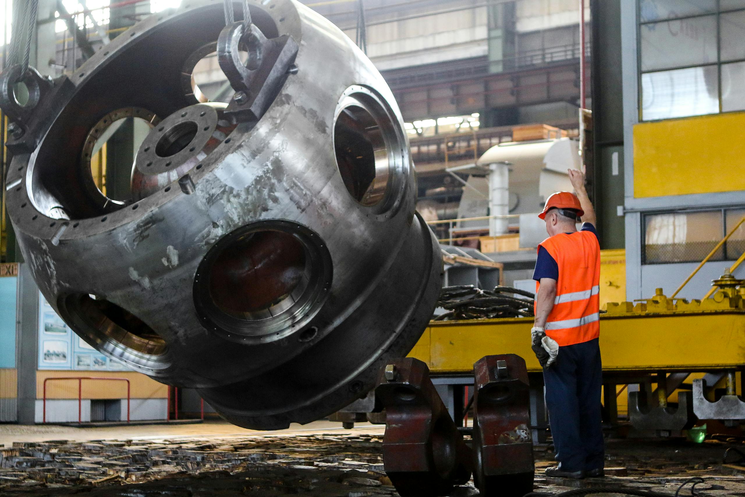 Worker in safety gear operating machinery inside an industrial plant.